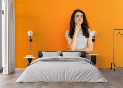 Pensive woman. Obesity problem. Body positive. Hard decision. Thoughtful confused overweight girl on orange background. Wall mural